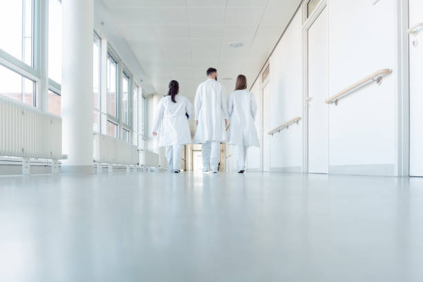 Three doctors walking down a corridor in hospital seen from behind